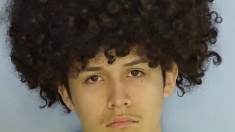 Mug shot of a hispanic male with an afro and a frown.