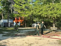 Deputies helping firefighters on the scene of a camper fire