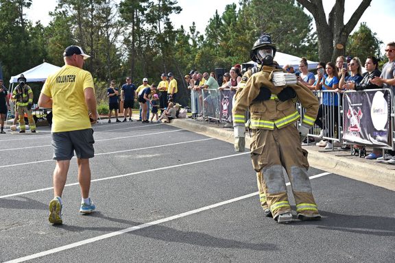 Firefighter dragging a large dummy across a parking lot