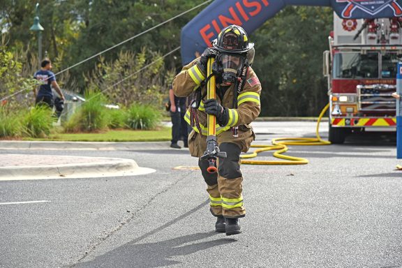 Firefighter running dragging a hose full of water