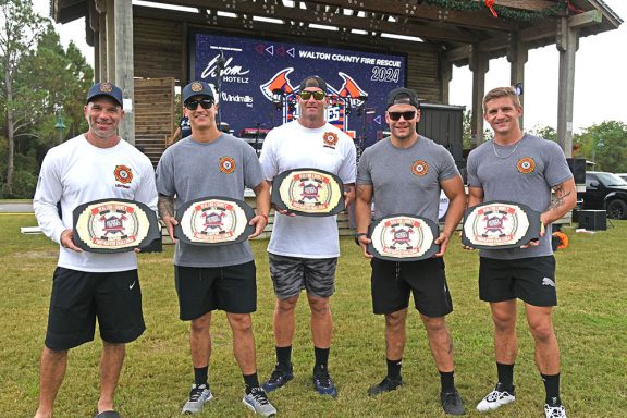 Five firefighters holding belts for winning the competition