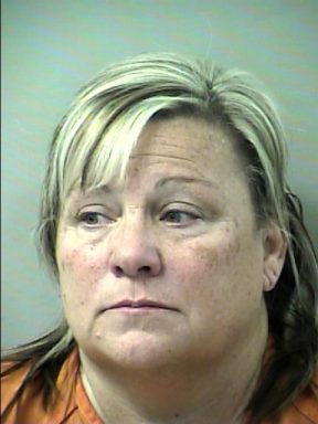 Mug shot of a white woman with blonde highlights wearing an orange jumpsuit.