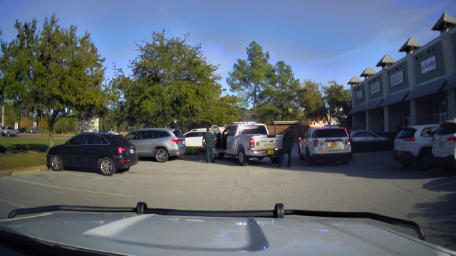 Two deputy patrol cars behind a white Jeep Grand Cherokee. 