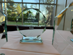 A glass award sitting on top of a table with "FSU Distinguished Young Alumni" etched on it.