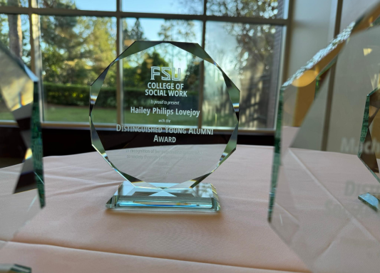 A glass award sitting on top of a table with "FSU Distinguished Young Alumni" etched on it.