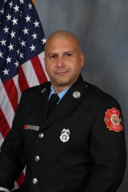 Hispanic male wearing a class A fire uniform with a coat and tie