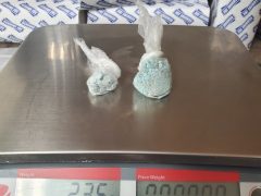 Photo of two plastic bags on a scale with blue pills inside.