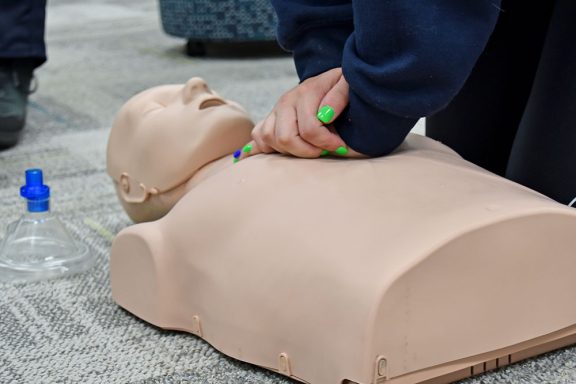CPR dummy lying on the ground while someone performs CPR