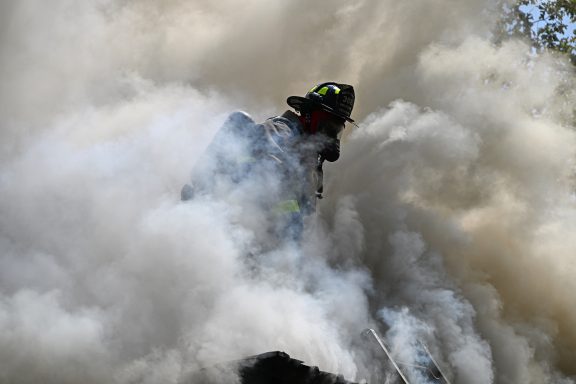 Firefighter on roof surrounded by heavy smoke