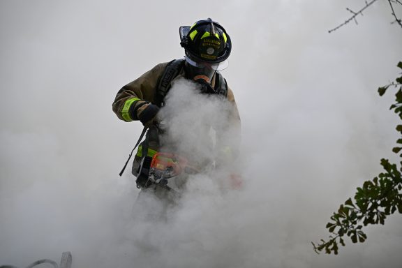 Firefighter holding saw surrounded by smoke