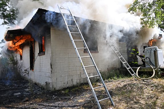 Smoke and flames coming out of a single-story white home