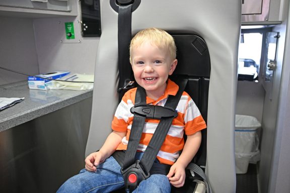 Little boy in a seat strapped in with child seat restraints in the back of an ambulance