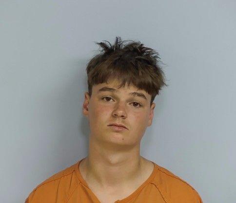 White male with disheveled brown hair wearing an orange jumpsuit