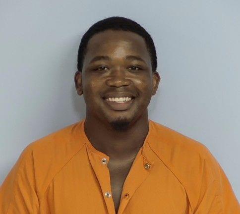 Black man with short black hair wearing an orange jail jumpsuit