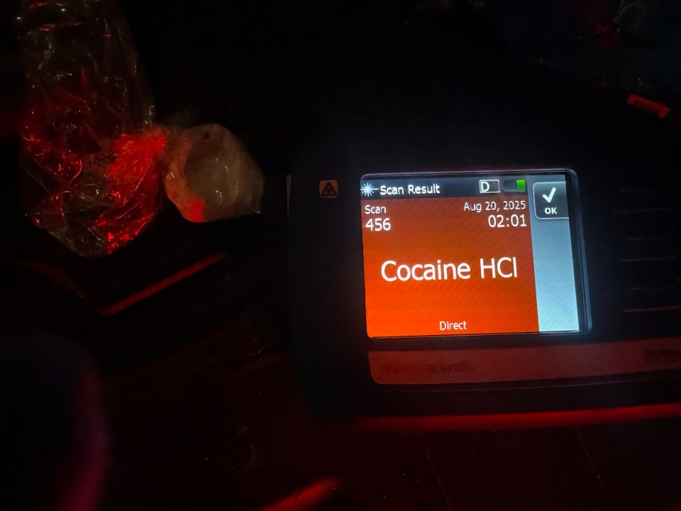 A red screen that says "COCAINE" with a plastic bag next to it with a white powdery substance inside.