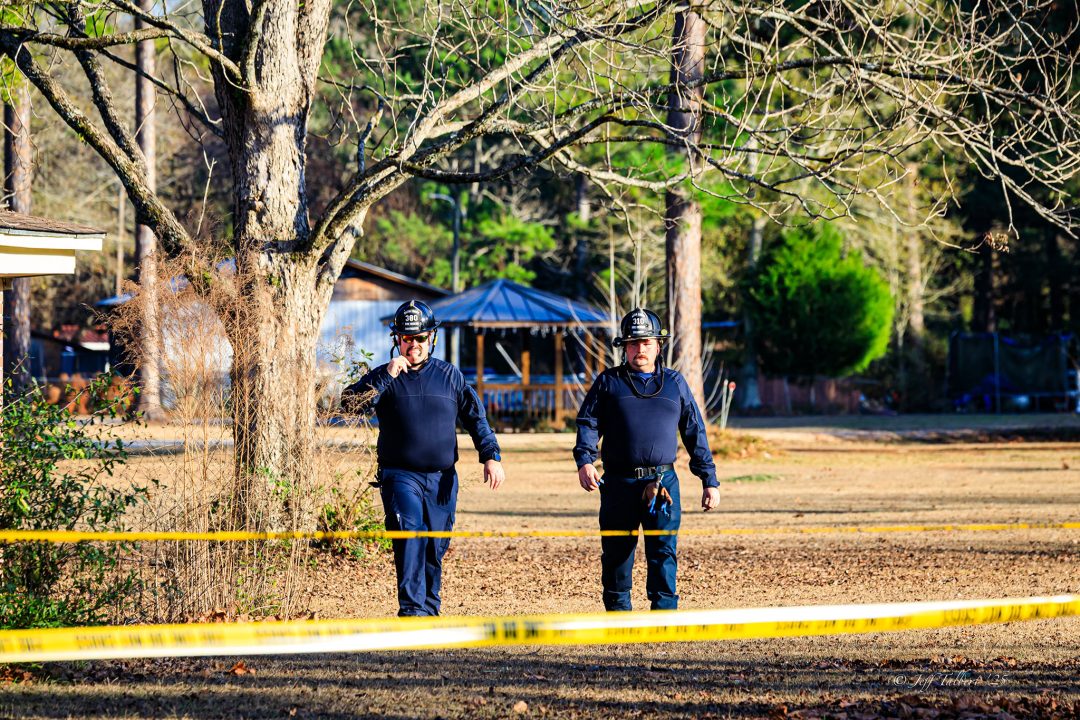 Two male firefighters walking towards a scene with yellow caution tape