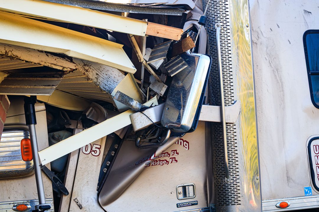 Close up of a semi truck that has crashed into a brick home