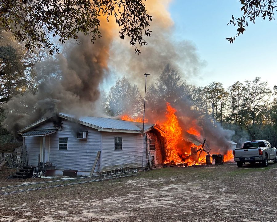 Single story white home with flames and smoke coming out of it