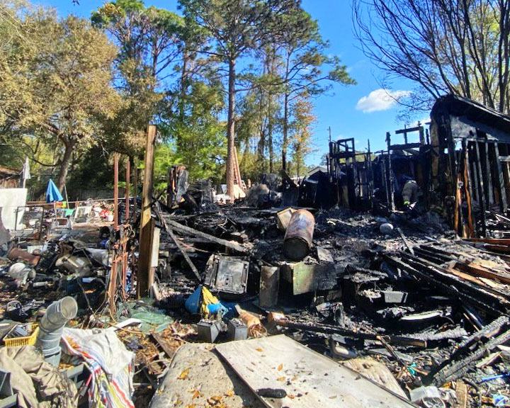 Aftermath of mobile home fire with charred debris all over the ground