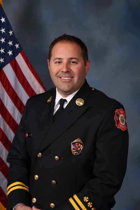 White male firefighter wearing a navy blue Class A uniform with a tie