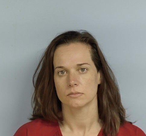 A person with medium-length brown hair is shown facing the camera against a plain light-colored background. The person is wearing a red shirt. The image is closely cropped to show the head and upper shoulders.