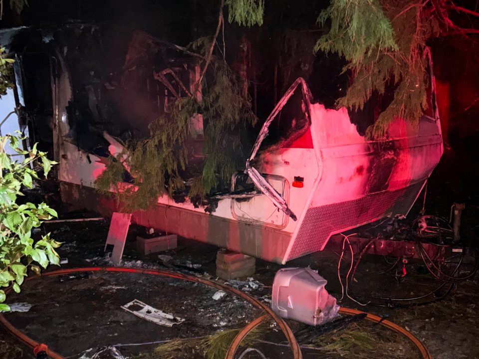 Night picture of a white camper with severe fire damage