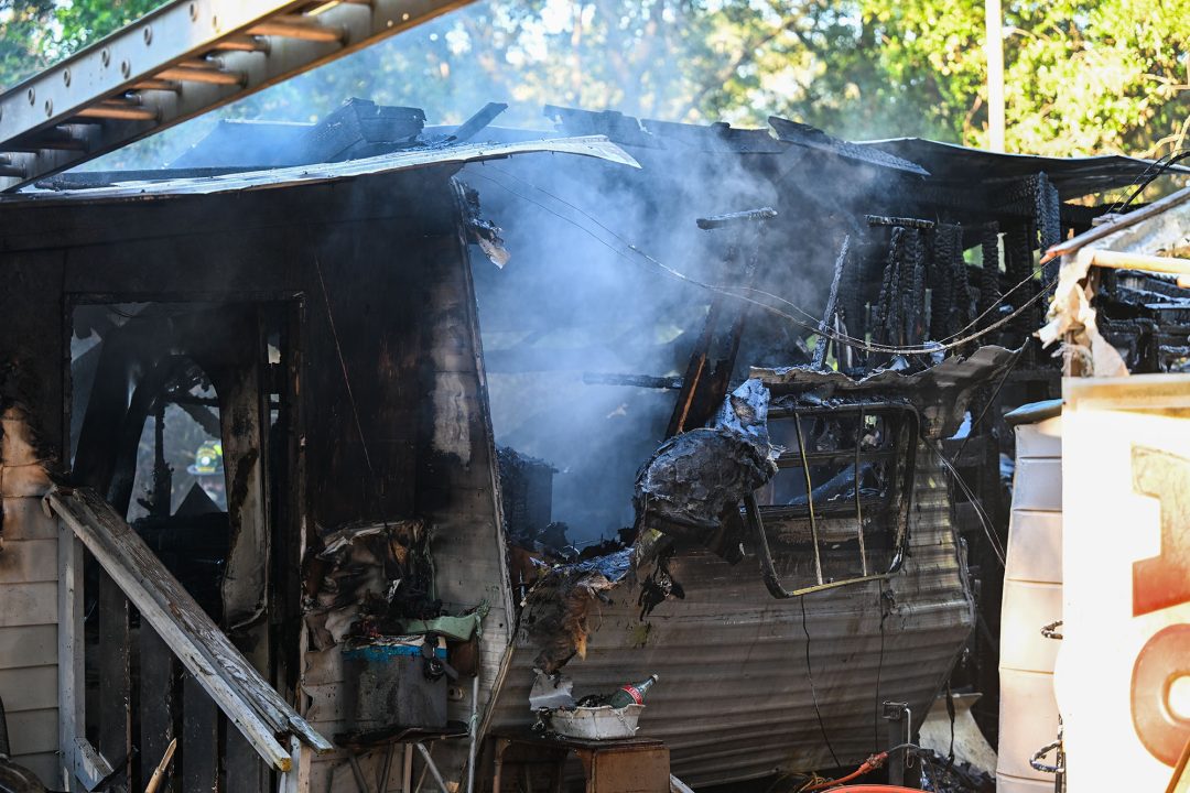 Smoke coming from a metal camper that has severe fire damage